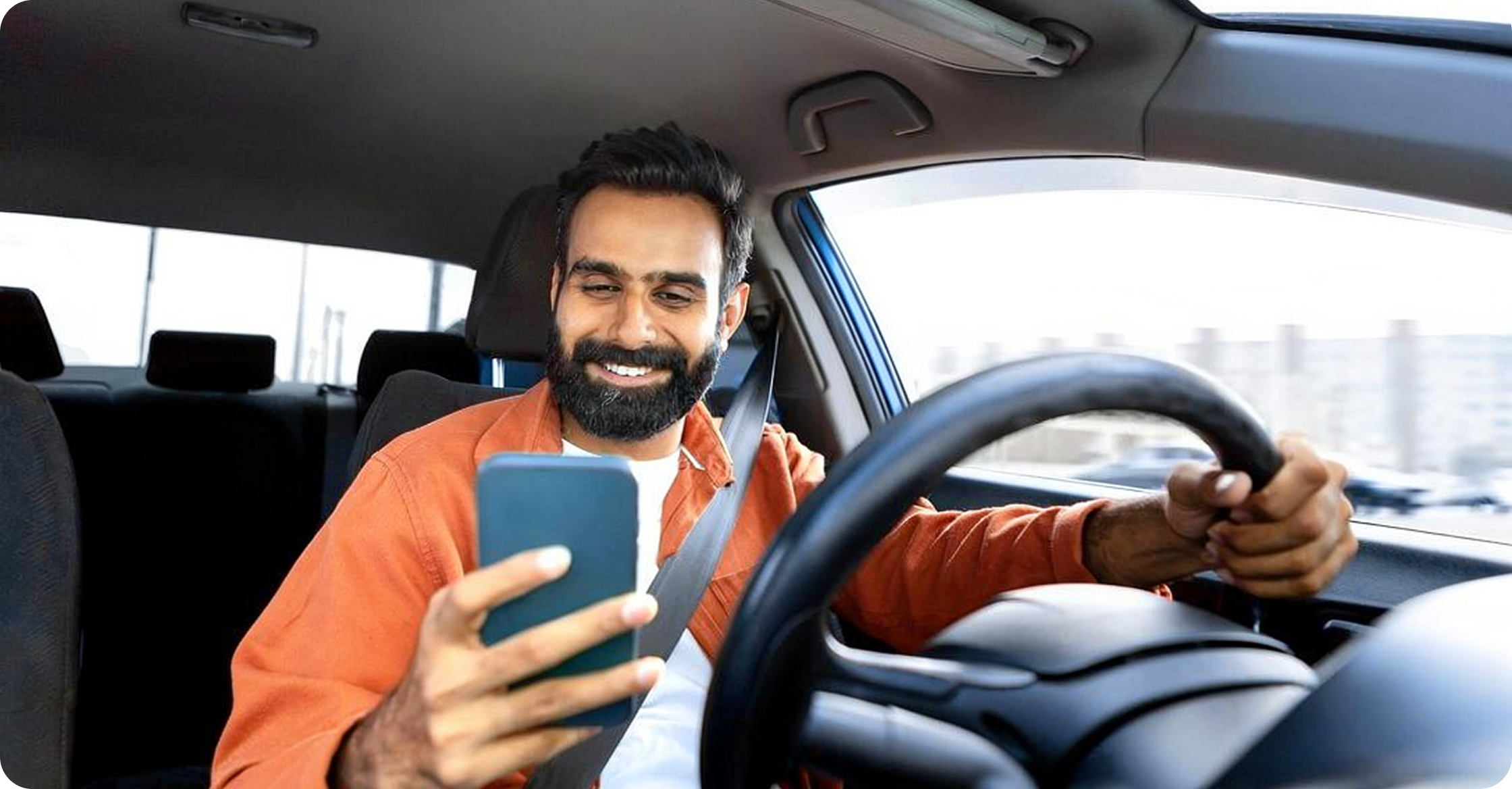 Driver smiling while checking phone inside a car