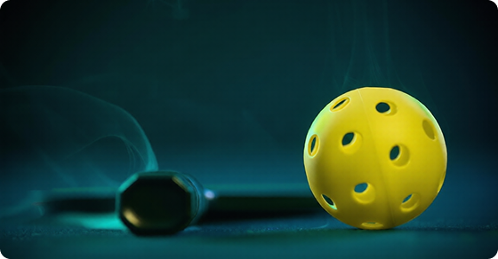 Yellow pickleball and paddle on a court